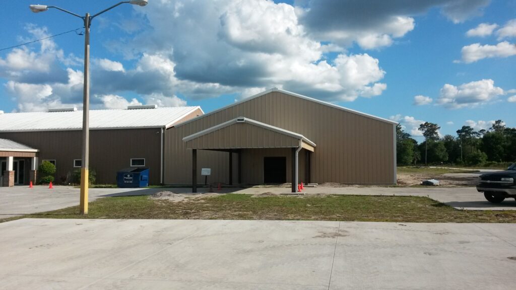 Covered red iron riding arena build by Buildings By Bill in Florida