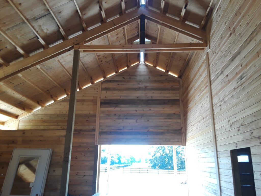 Interior of a post frame barn showing posts and trusses, built by Buildings By Bill